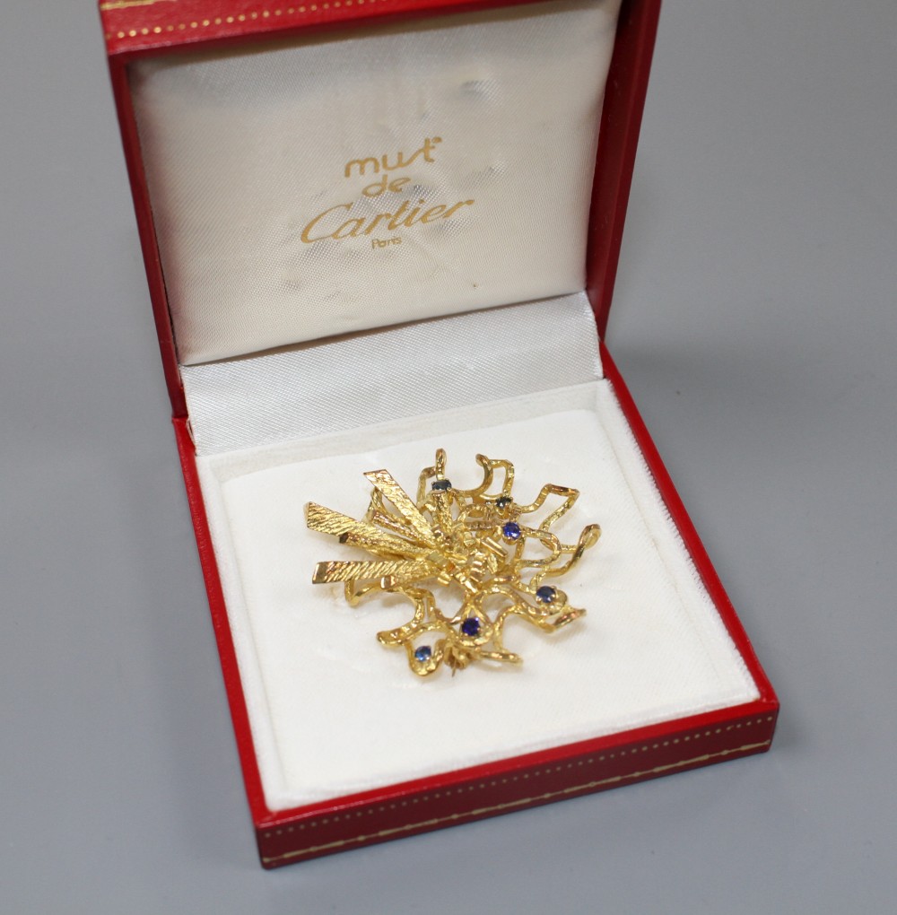 A 1970s? unmarked yellow metal and six stone sapphire set modernist scroll brooch, 46mm, gross weight 17.5 grams.